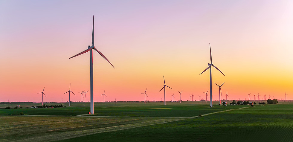 Photograph of wind turbines with pink sky in background
